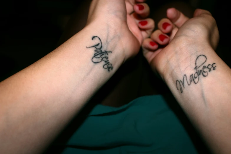 two ladies holding hands in their hands with name tattoos