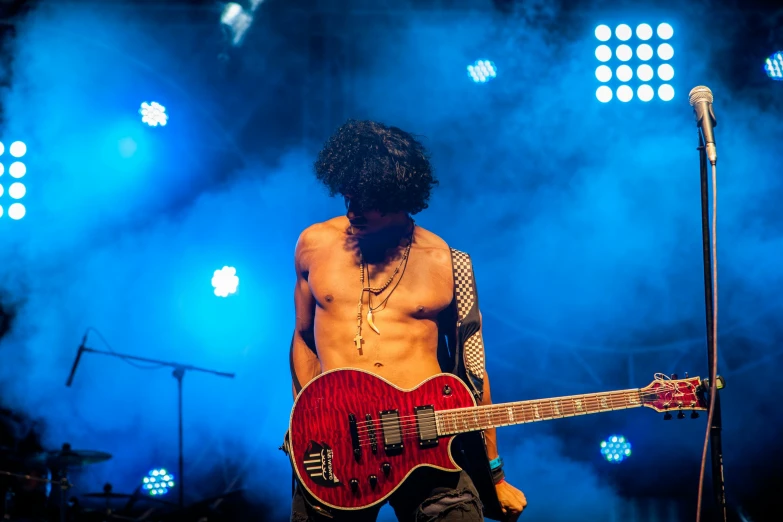 an image of a man with long hair playing guitar