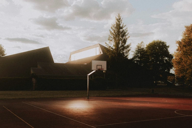 a basketball hoop at dusk with lights shining on it