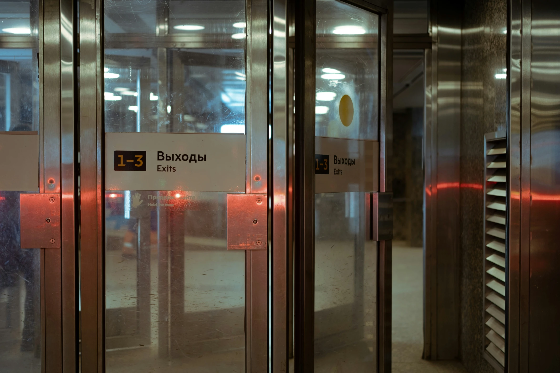 two people are standing by the large glass doors