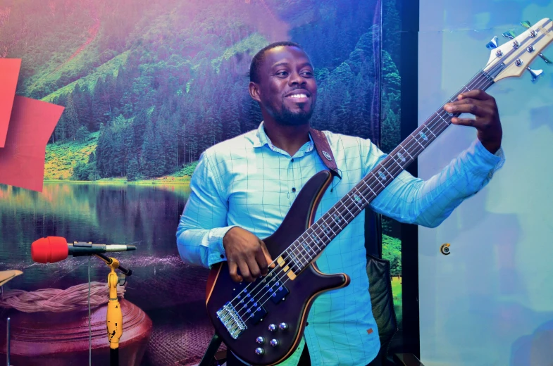 a man smiles while holding a guitar in his hand