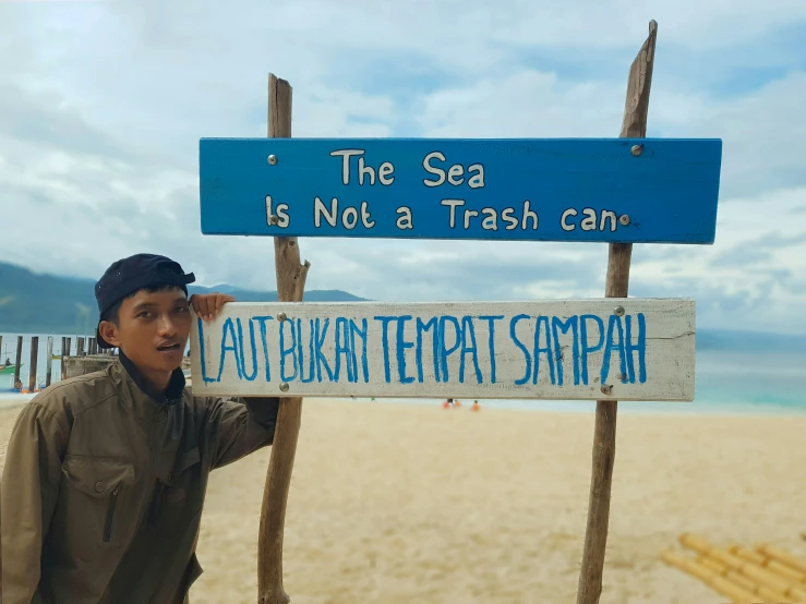 a  standing beside a sign that says the sea is not a trash can