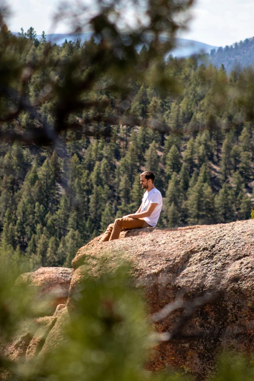 a man sitting on top of a large rock