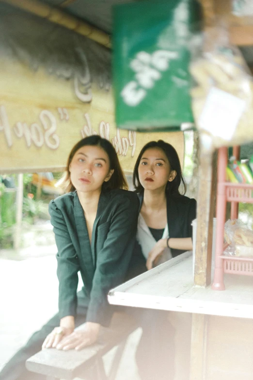 two women are looking to the sky, with a view of signs hanging above them