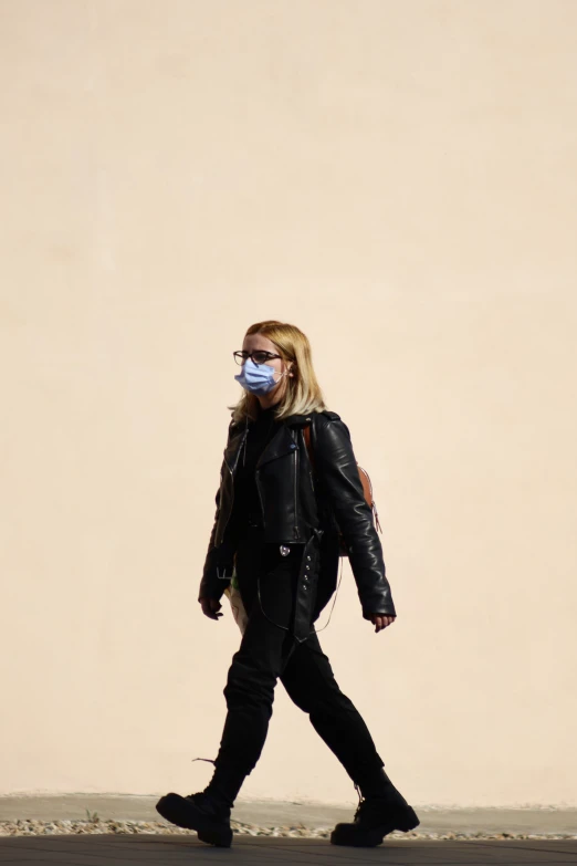 a woman walking down the street wearing a face mask