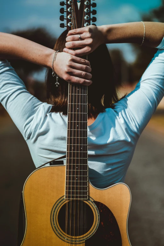 a woman wearing white is holding an acoustic guitar