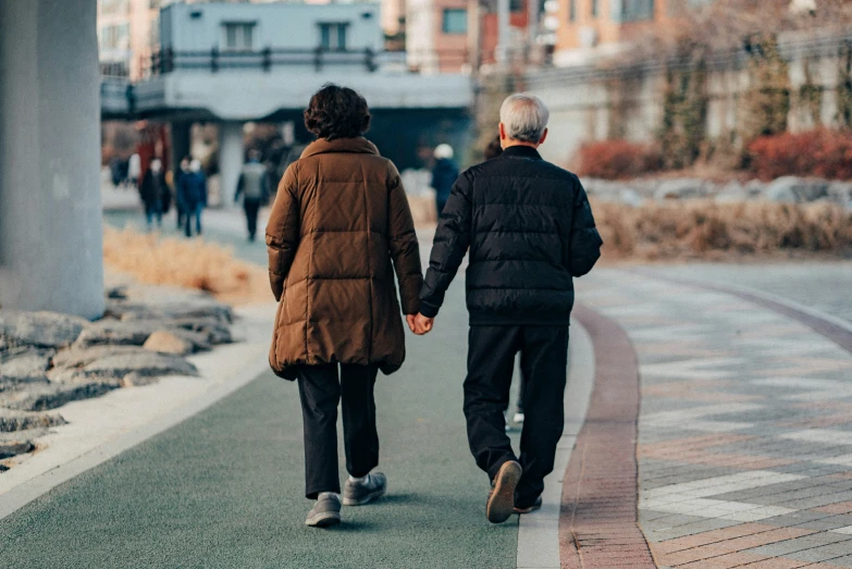 two older people are walking down the street