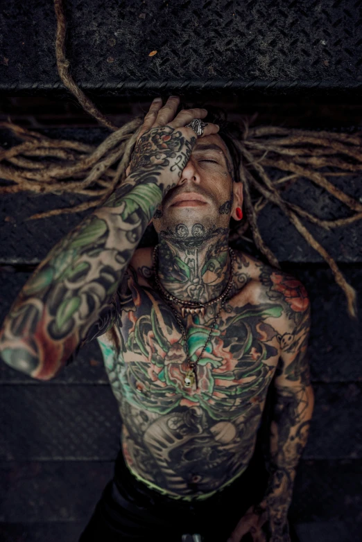 a man with tattoos is covering his eyes from the sun