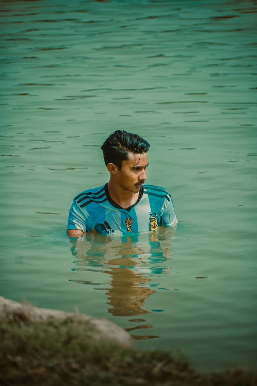 a man standing in a lake next to a hill