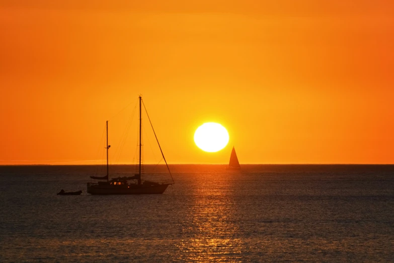 two sail boats are sailing across a large body of water