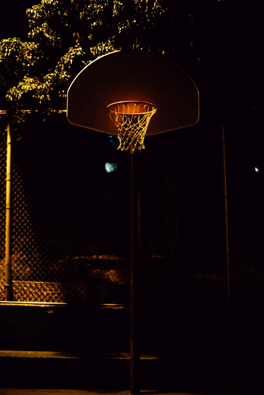 a basketball hoop with a light on it in the dark
