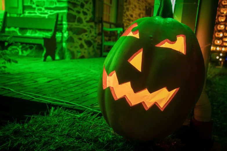 a large green pumpkin with glowing faces lite up at night