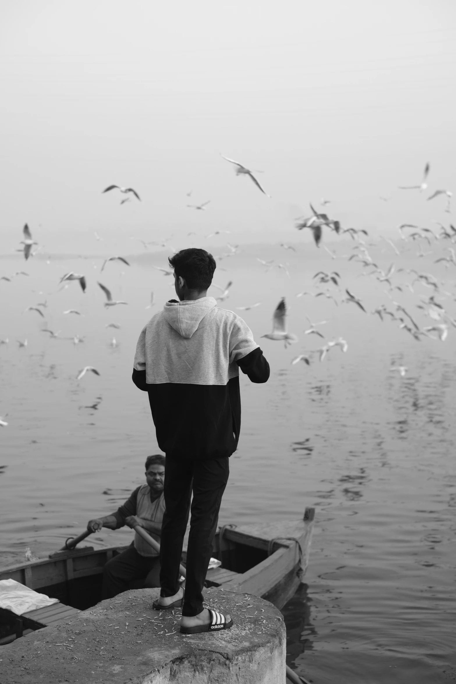 a man and woman standing on the water watching birds