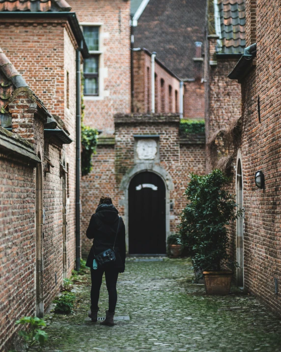 man in back with black jacket and white clock on building in alley way