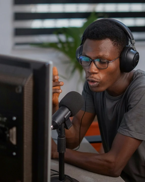 young black man listening to headphones in front of a computer screen