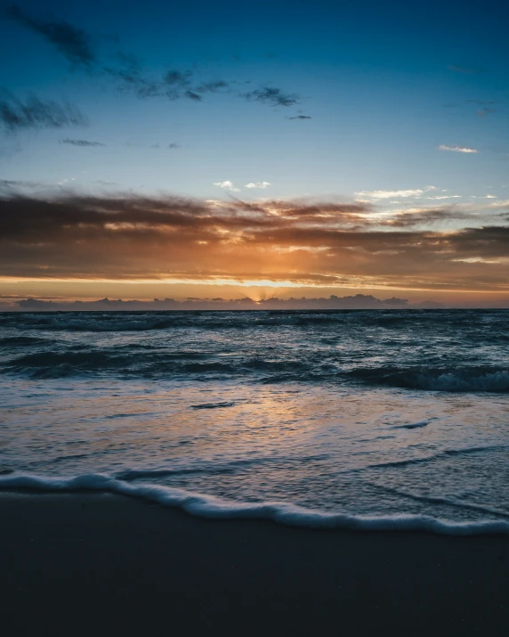 a po taken from the beach at sunset with the sky and ocean in the background