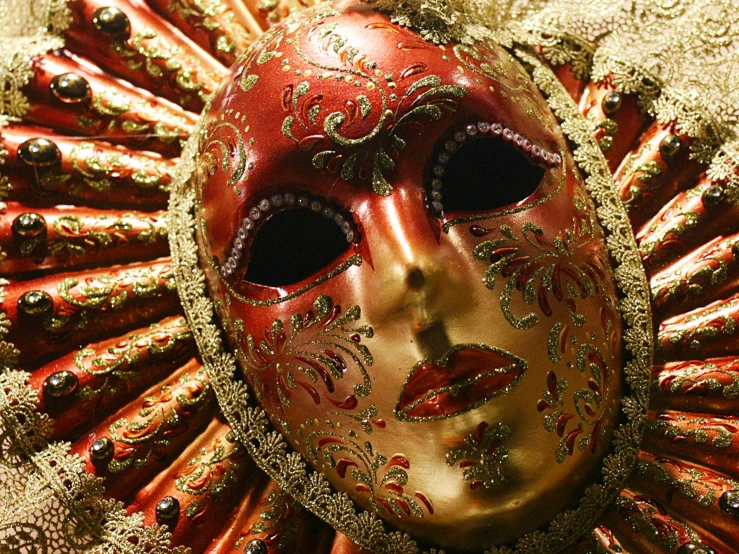 the face of an ornate red mask is adorned with jewels