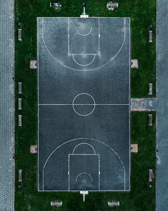 a basketball court sitting in the middle of a green area