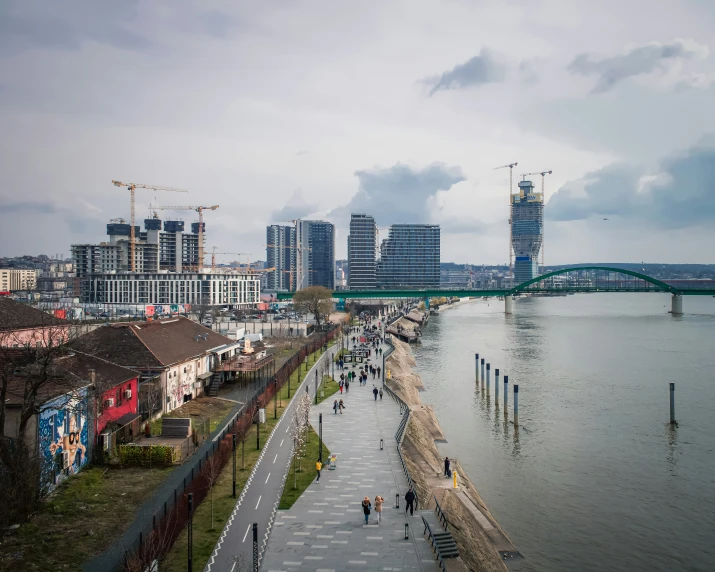 many people walk on a long walkway next to the water