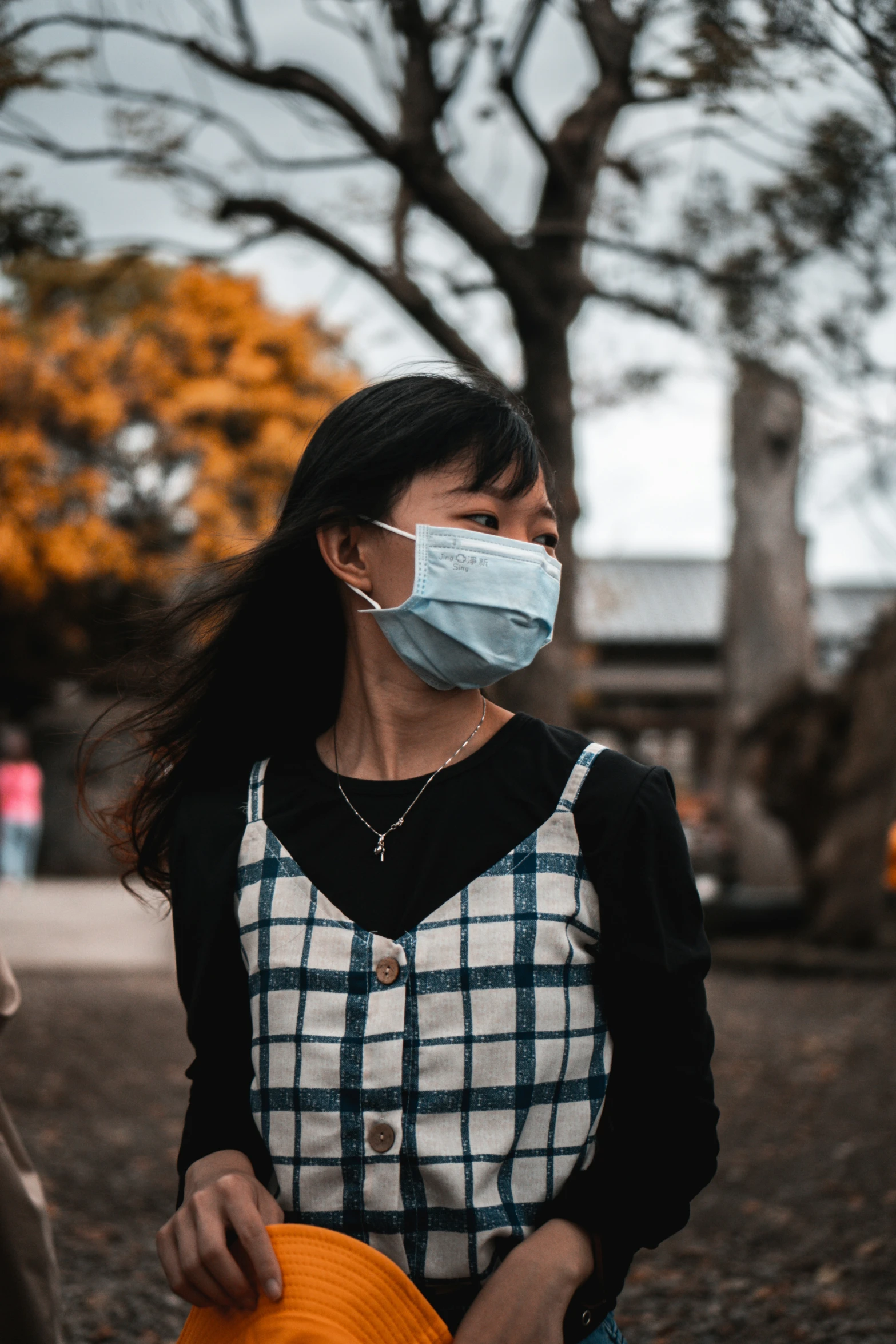 a woman wearing a mask while holding an orange umbrella