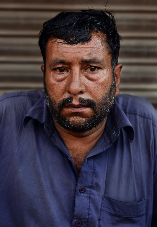 a close up of a man with a beard wearing a blue shirt