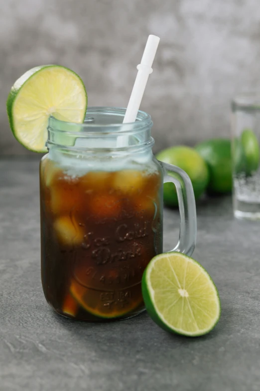 a beverage with limes next to it and a glass of soda