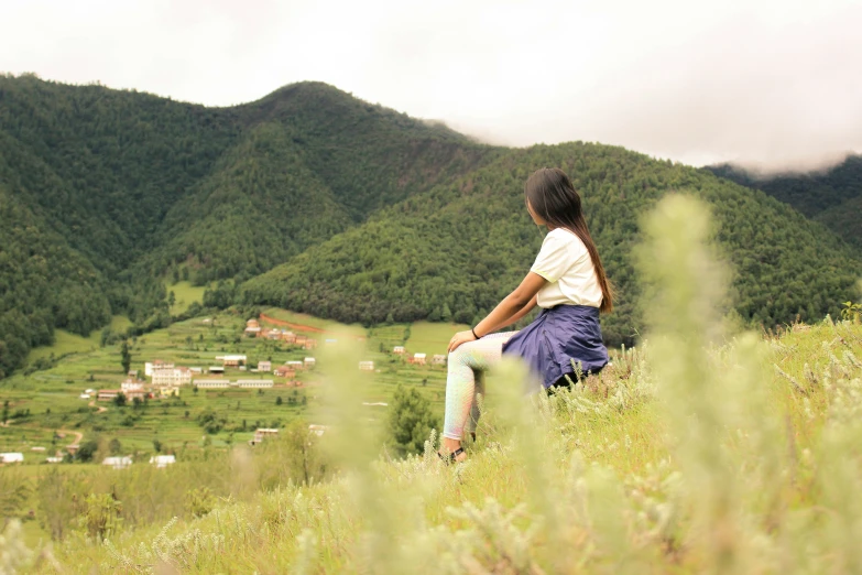 the girl sits down watching the mountains in the distance