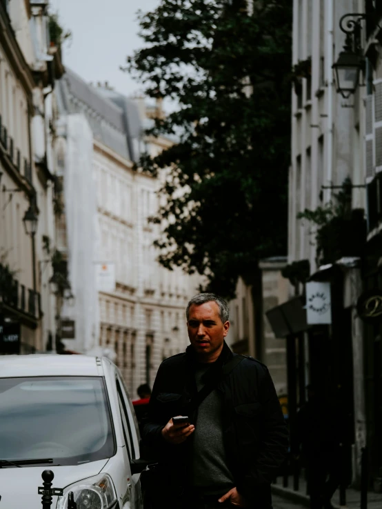 a man in grey sweater standing by a silver van