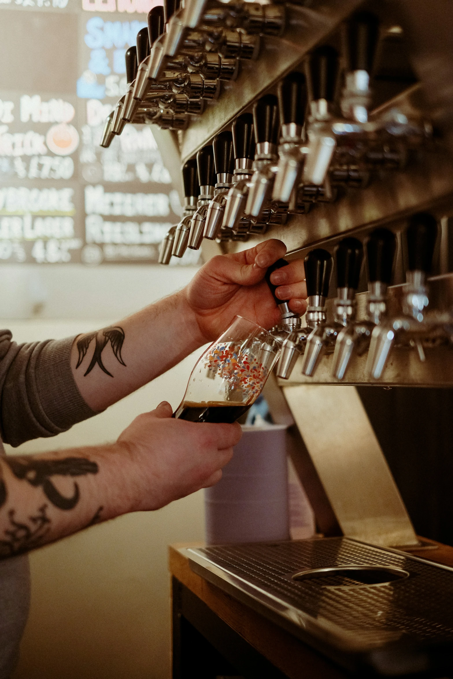 a man in grey shirt pouring a glass of beer