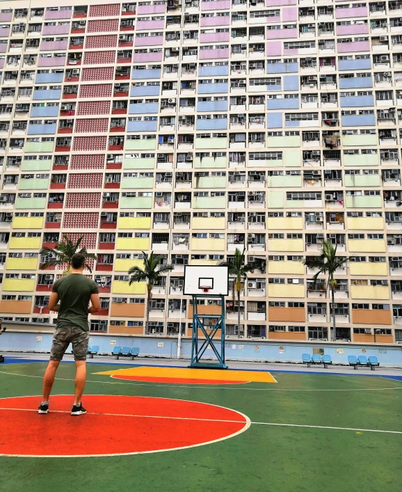 a man in an overcoat playing basketball outside a high - rise building