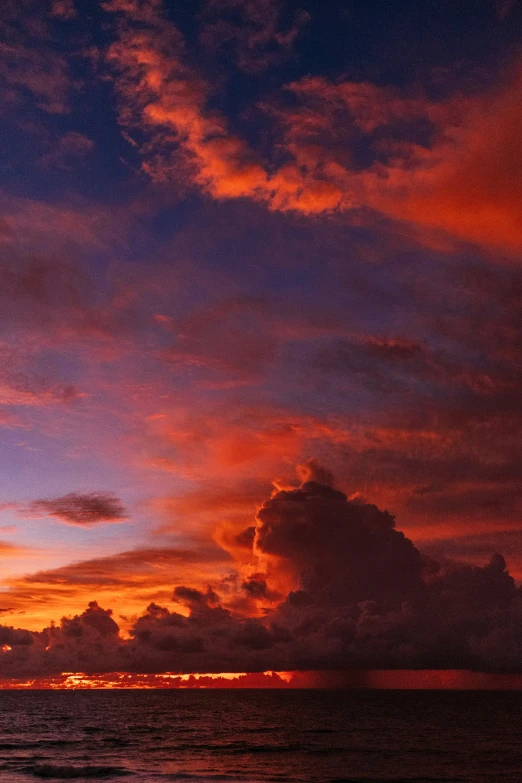 a view of a sky with clouds and water at night