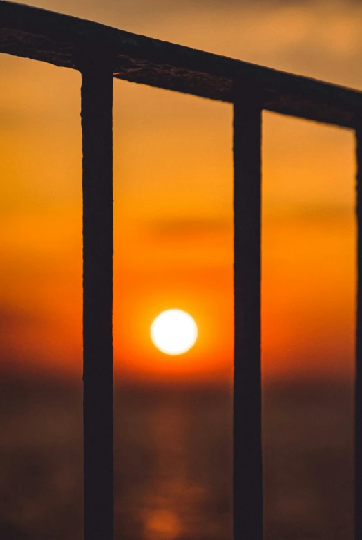 a fence and some water in front of a sunset