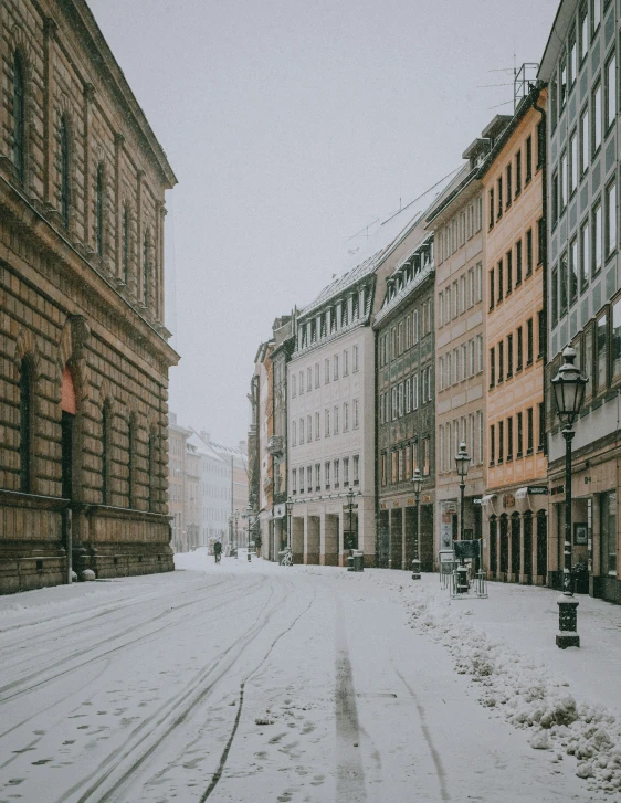 snowy streets with buildings and benches are shown