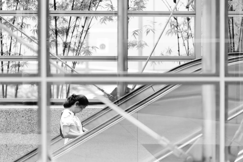 woman on escalator in building reflecting outside