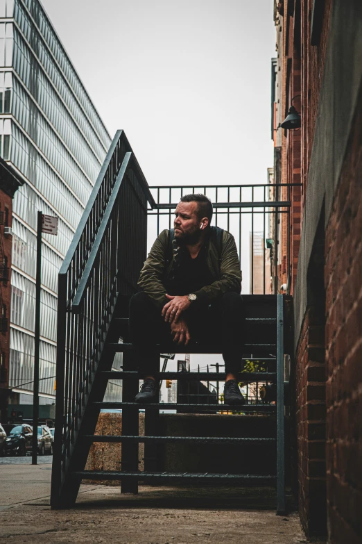 a man sitting on top of a wooden bench next to some tall buildings