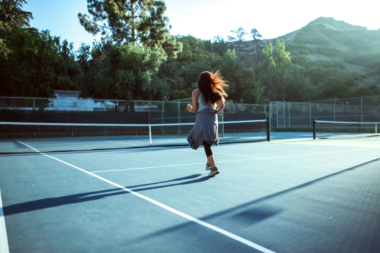 a girl on a tennis court running and playing tennis