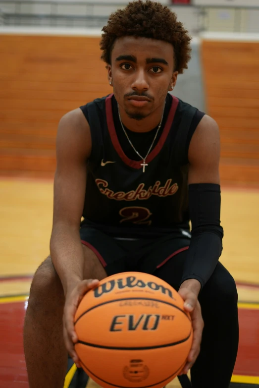 a young man is sitting in the court holding a basketball