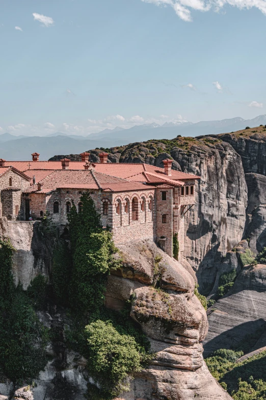 the mountaintop view of an old house sits on rocks