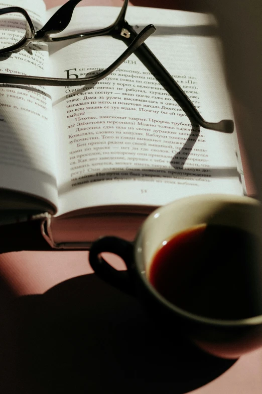 book and glasses on table with light from above