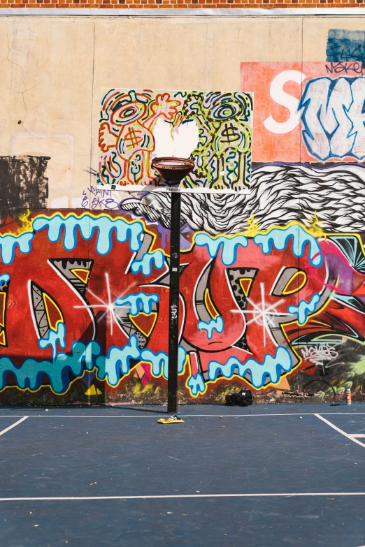 an empty basketball court next to a graffiti covered wall