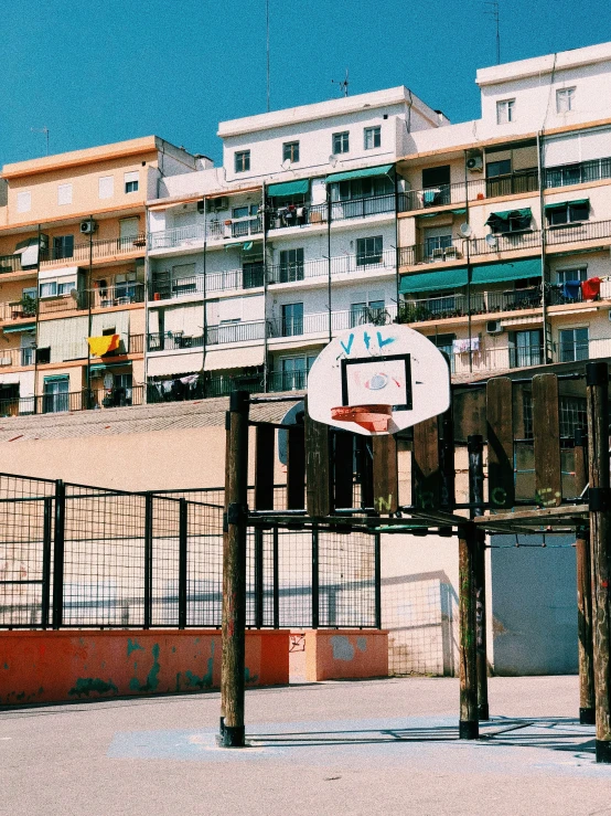 an old basketball hoop with multiple balconies in a city