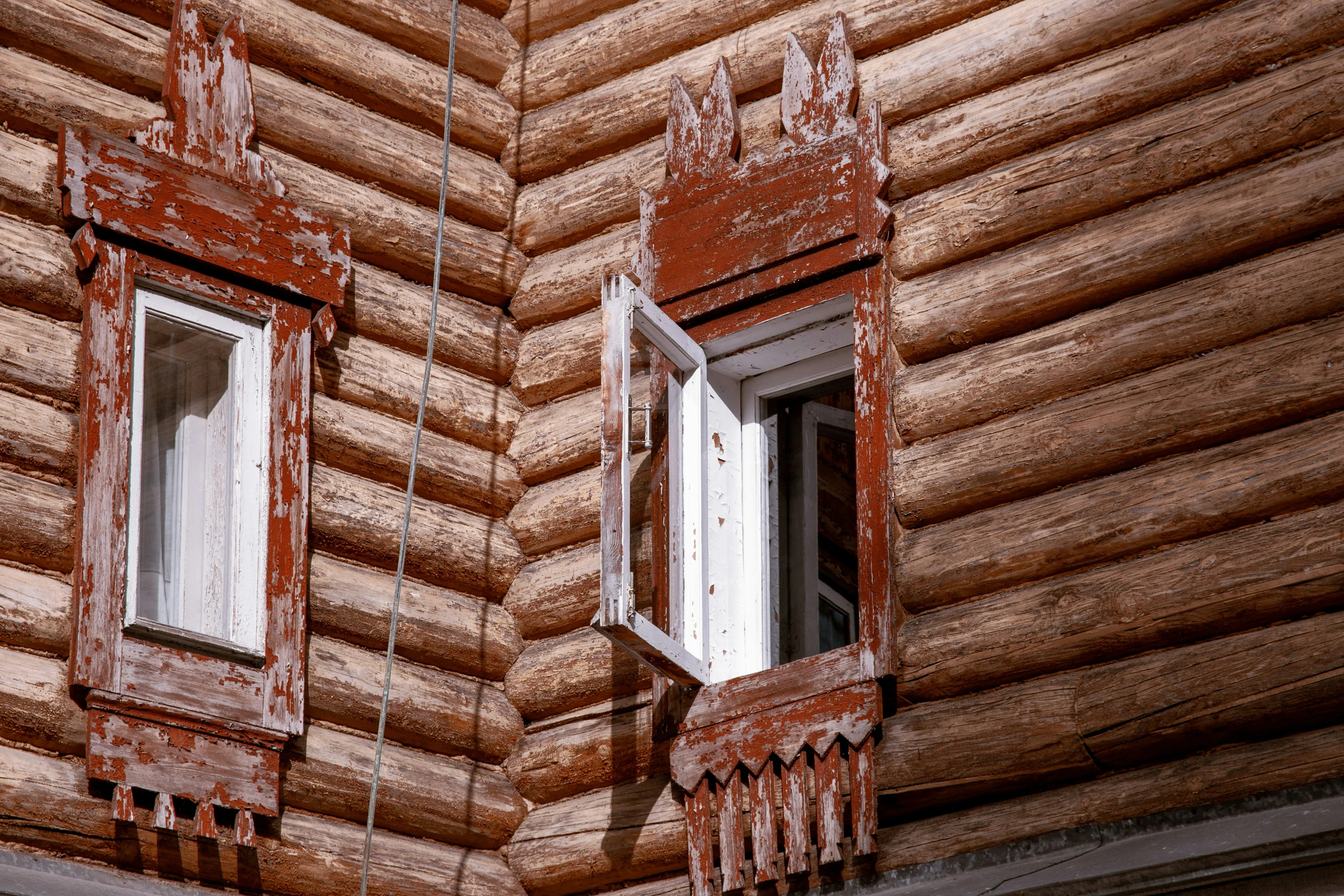 two windows in a log cabin with wooden siding