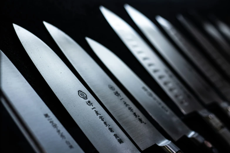 many large knives lined up on a table