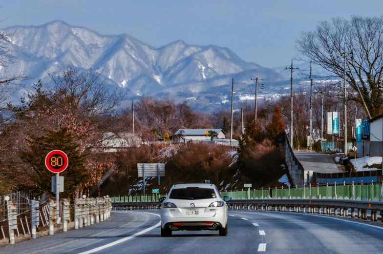 white car driving down a road towards a mountain range