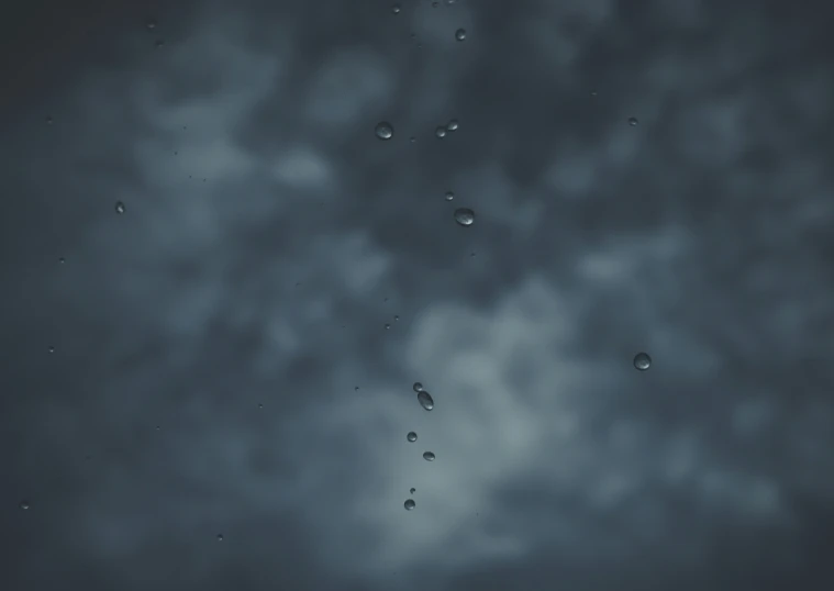 a blue cloudy sky is lit by rain drops