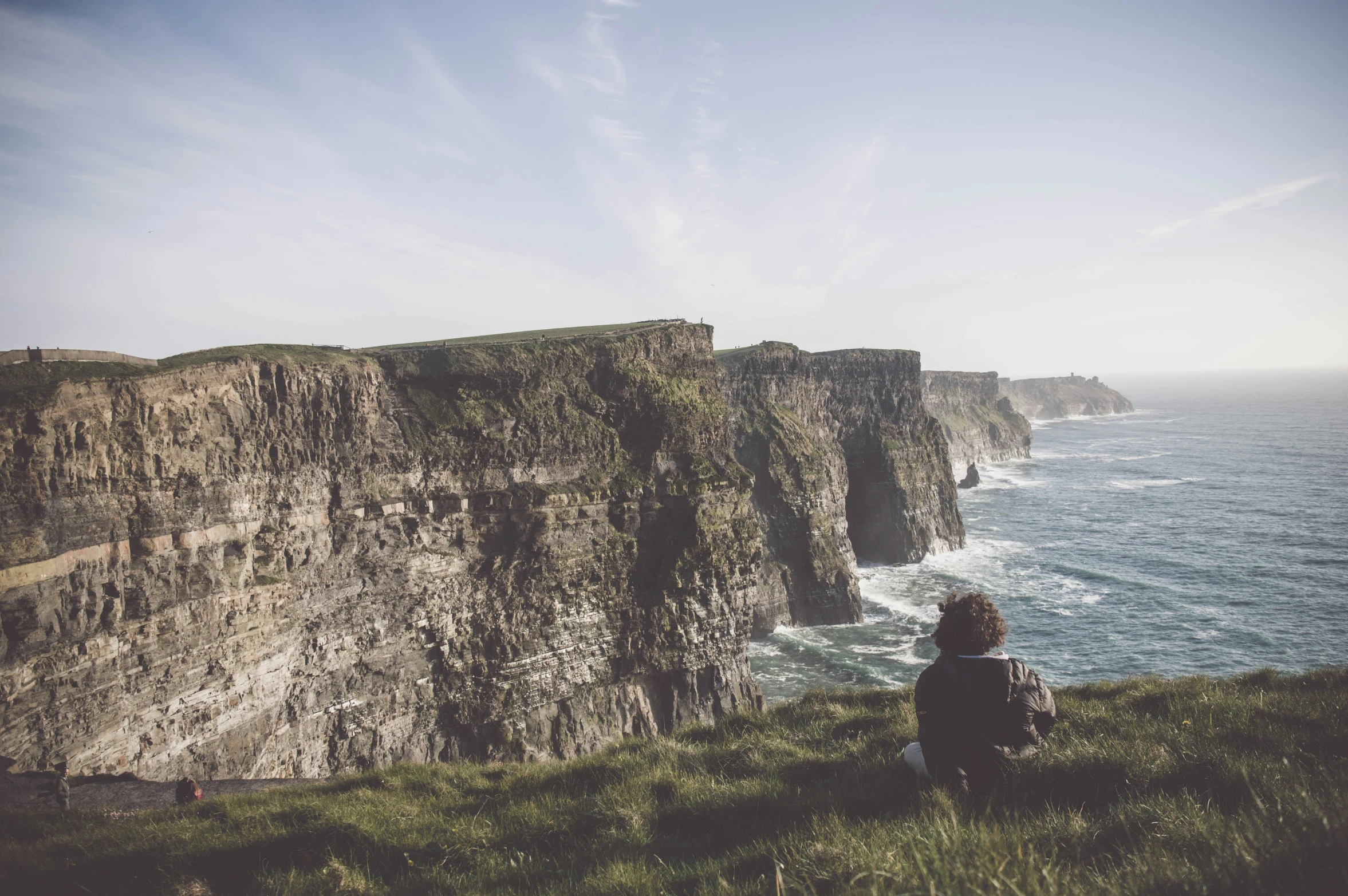 a person sitting on a hill overlooking the water