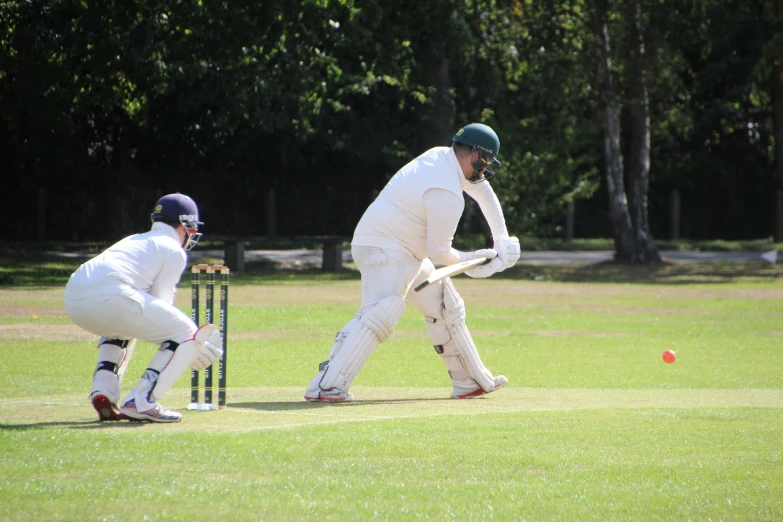 a young man wearing a helmet and gloves prepares to hit a ball during a cricket game