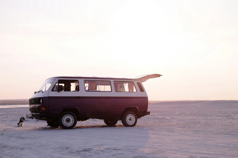 a van is parked on the beach with surfboards mounted on its roof