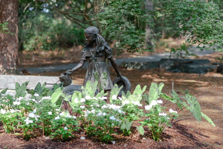 a statue of a woman with a child by some white flowers