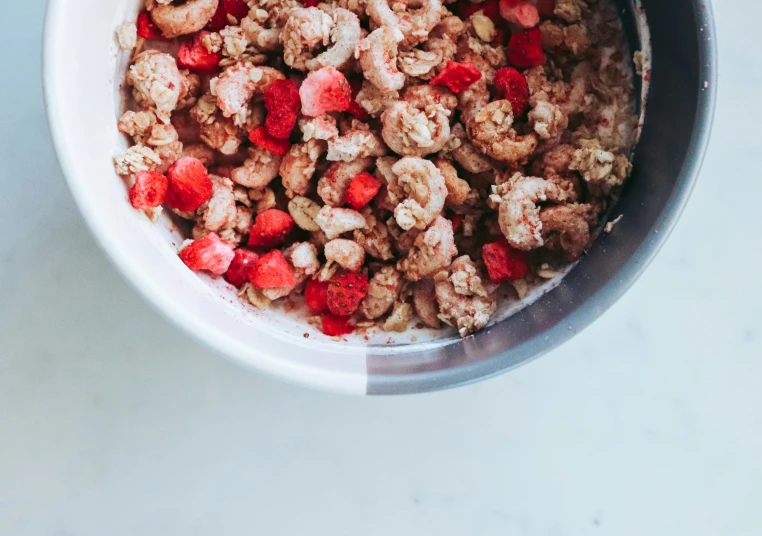 a bowl of granola is topped with strawberries